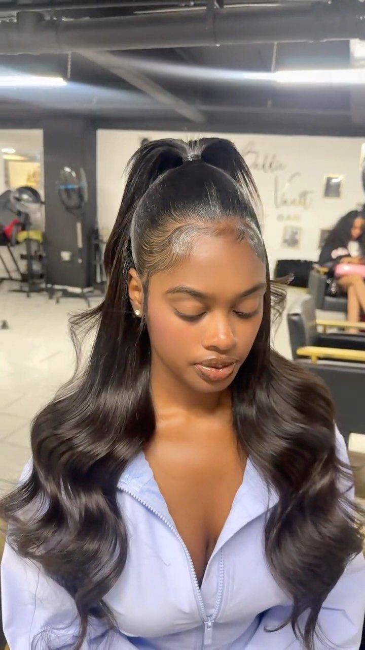 Woman with long wavy dark hair styled in a high half-up ponytail.