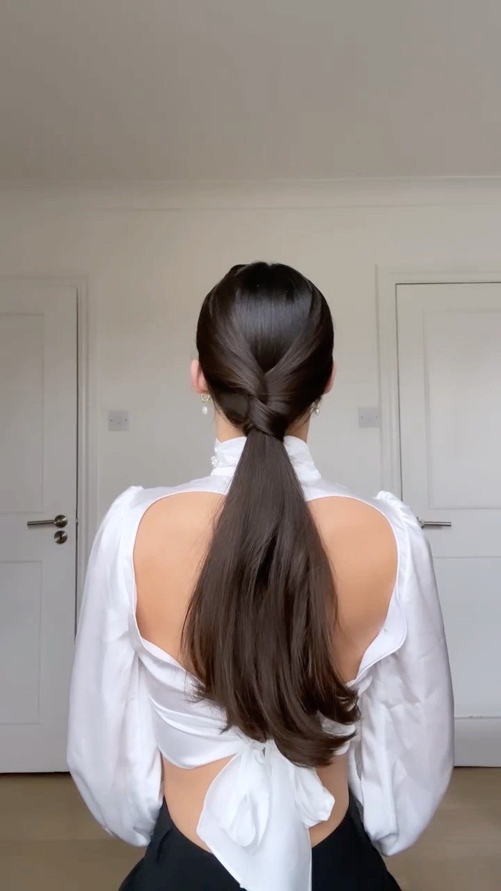 Woman from behind with long brown hair styled in a sleek low ponytail.