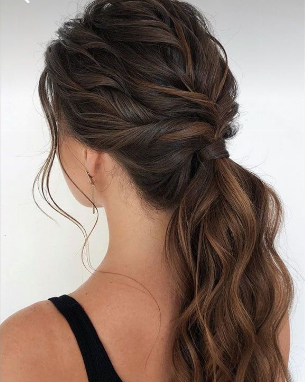 Woman with brown hair in a loose, textured messy ponytail with wavy curls.