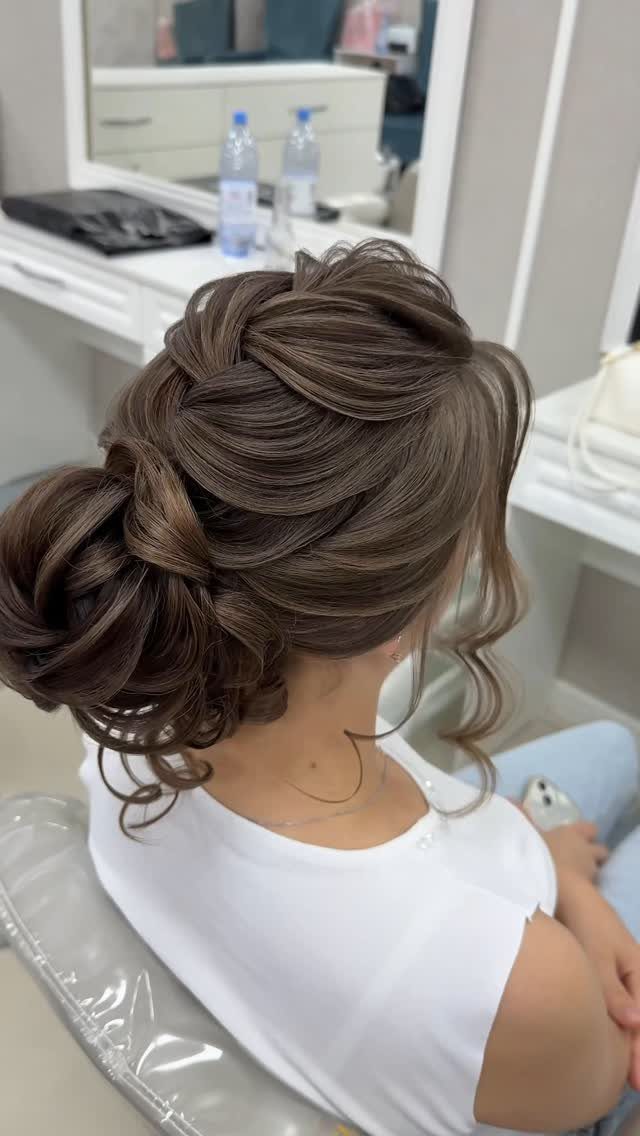 Woman with brown hair in an intricate braided updo with loose curly tendrils.