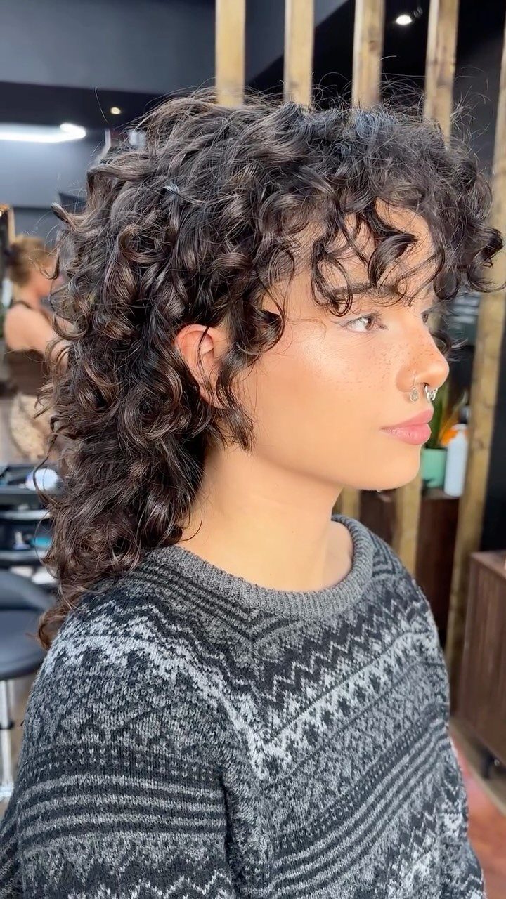 Woman with a curly shag haircut featuring voluminous layers and curly bangs.