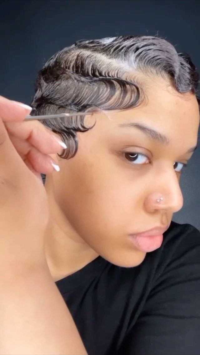 Woman with sculpted finger waves using a comb to style her short hair.