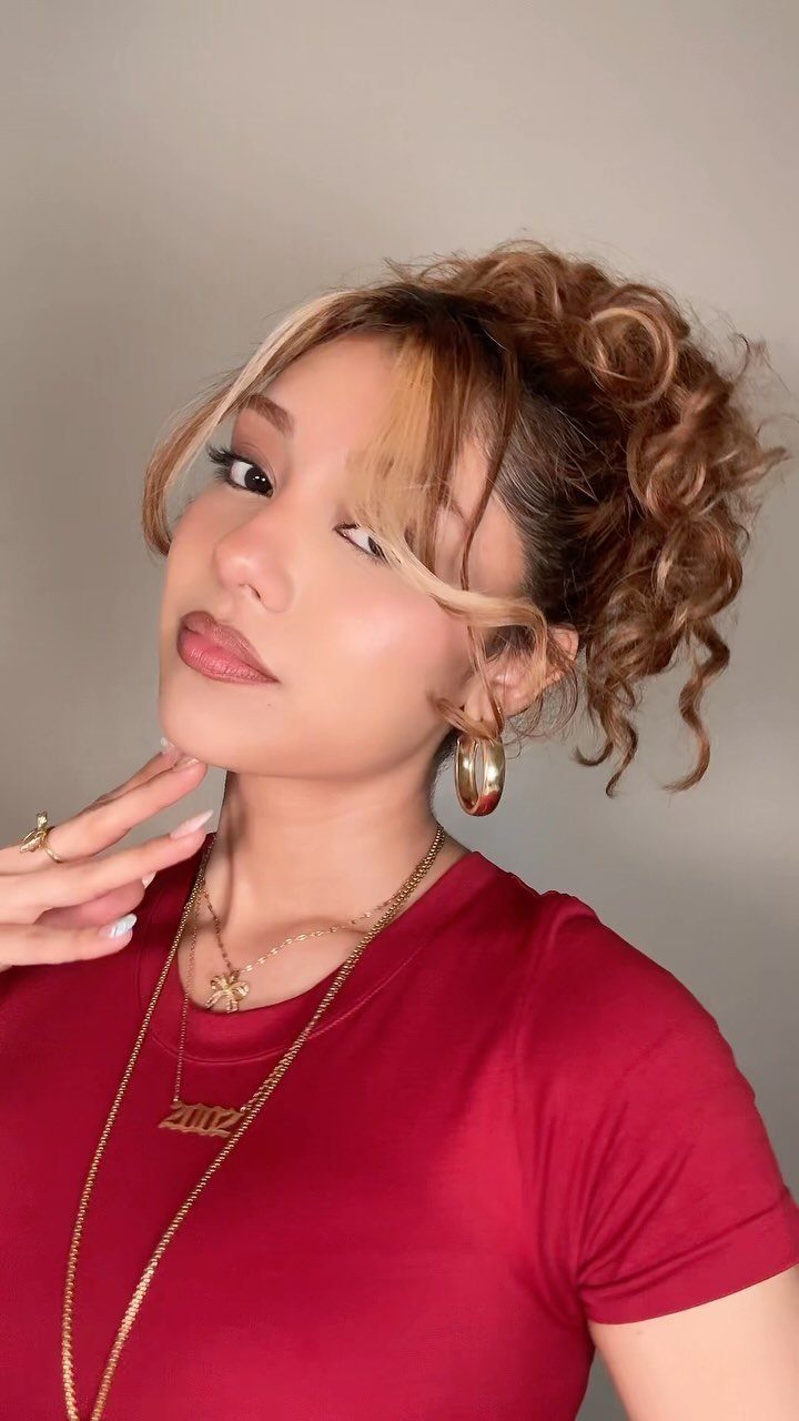 Woman with curly brown hair in an updo and loose curly bangs.