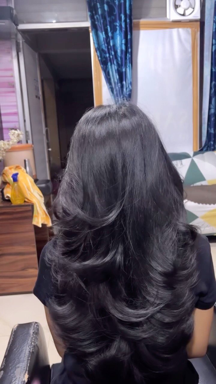 6 Hairstyles for Moms with Long Hair That Are Easy to Wear 1 Long black hair styled in a voluminous butterfly haircut with feathery layers.