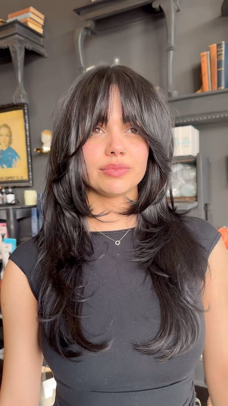 6 Hairstyles for Moms with Long Hair That Are Easy to Wear 5 Woman with long layered black hair and full bangs wearing a black top.