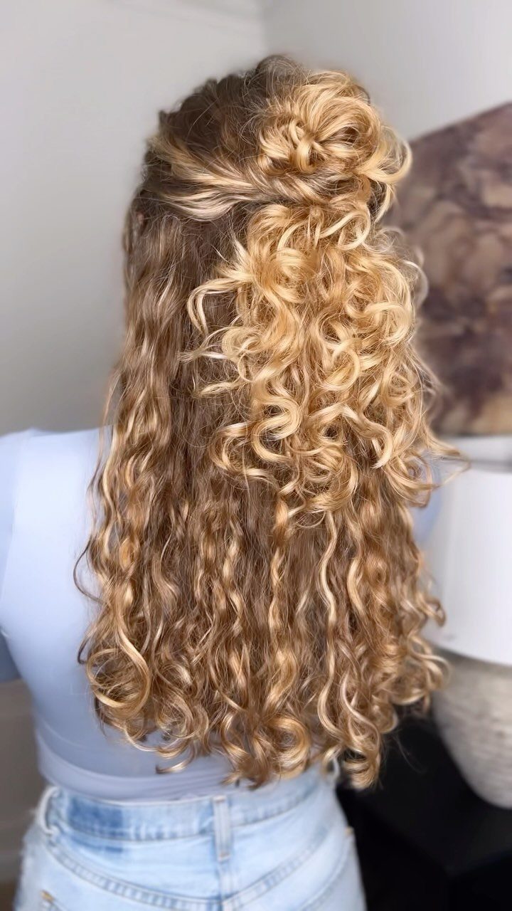 Curly blonde hair styled in a half-up bun with loose curls flowing down.