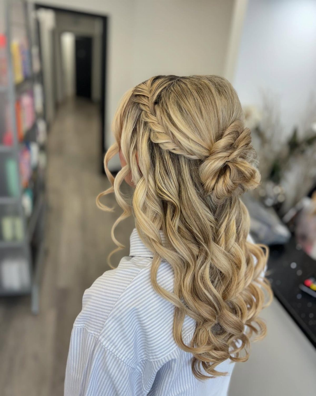 Blonde curly hair styled in a half-up fishtail braid and small bun.
