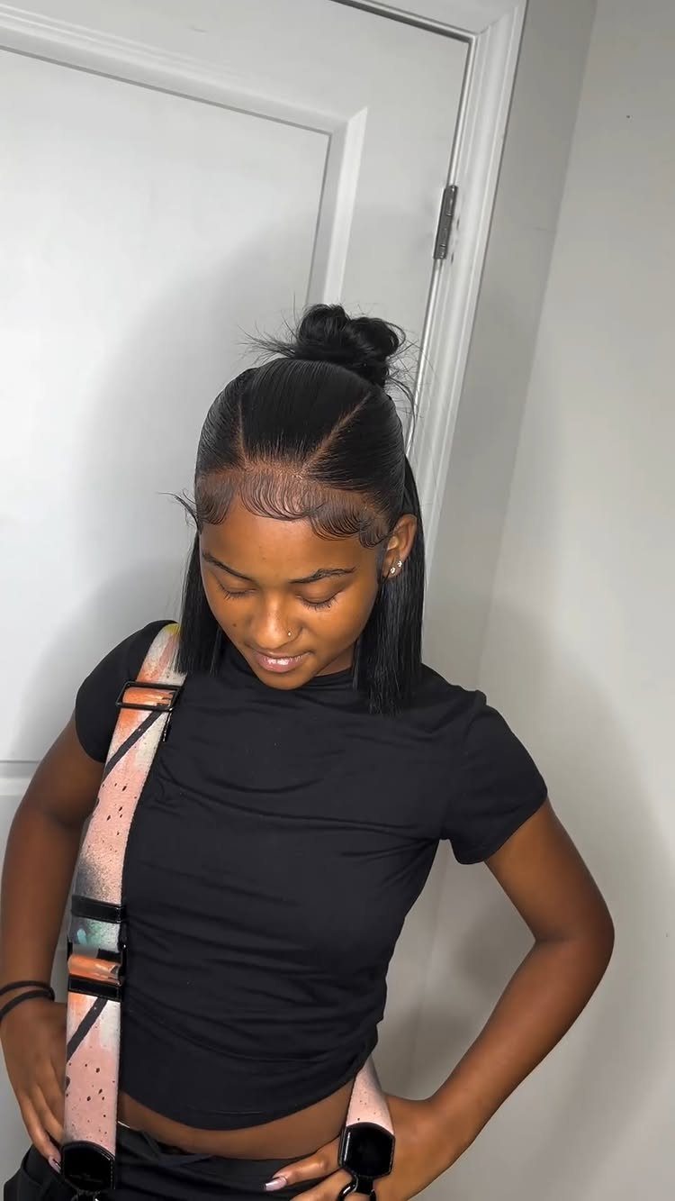 Woman with a sleek half up half down bun hairstyle and black t-shirt.
