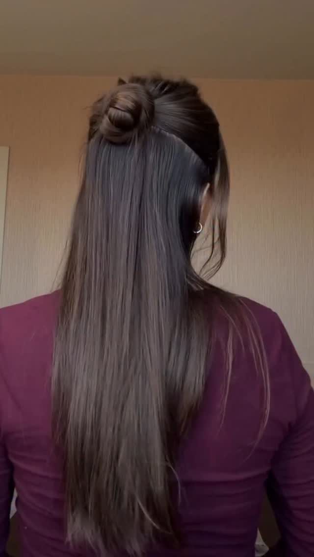 Woman with long brown hair styled in a half-up small bun.