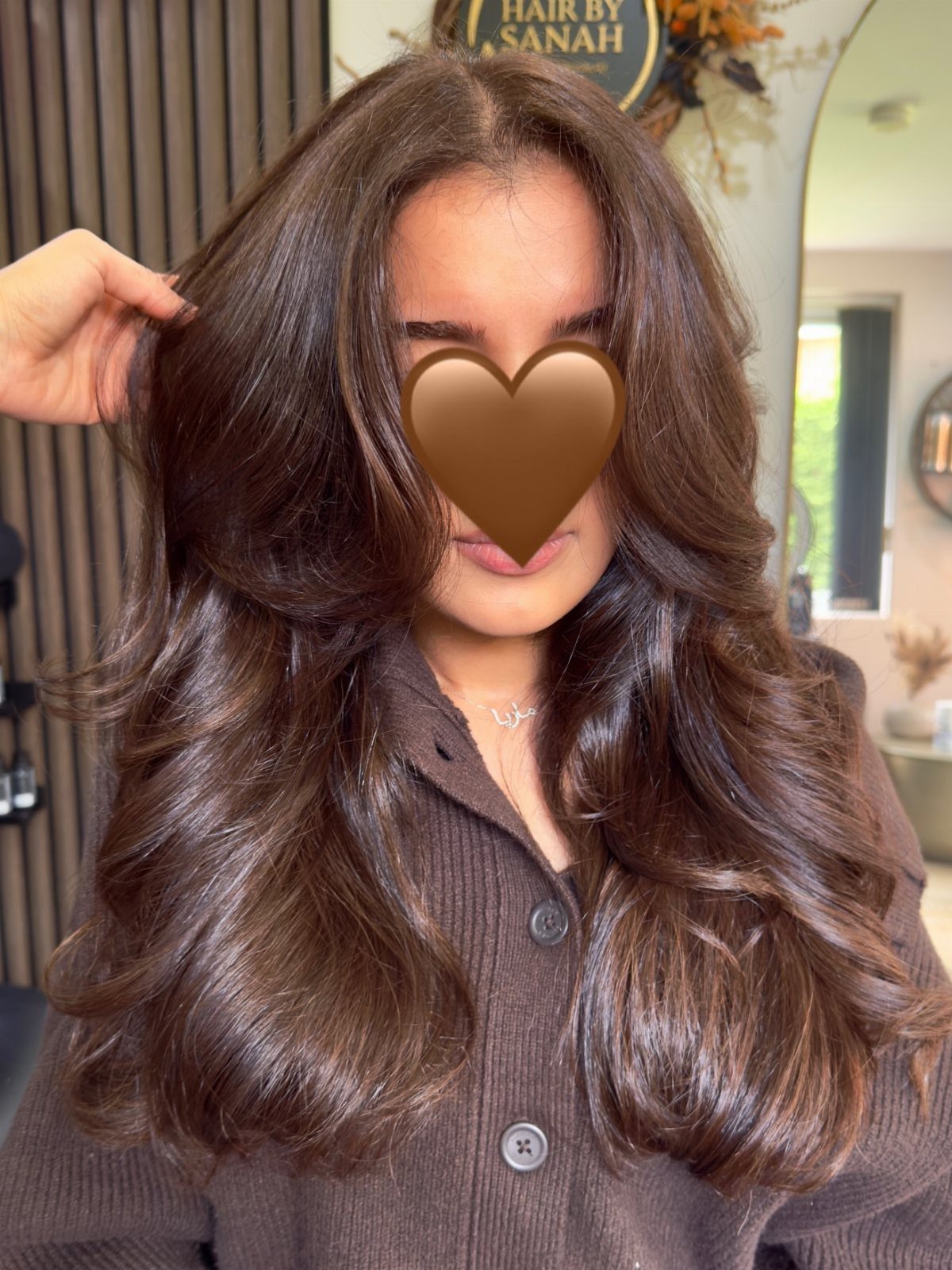 Woman with long wavy hazelnut brown hair wearing a brown ribbed cardigan