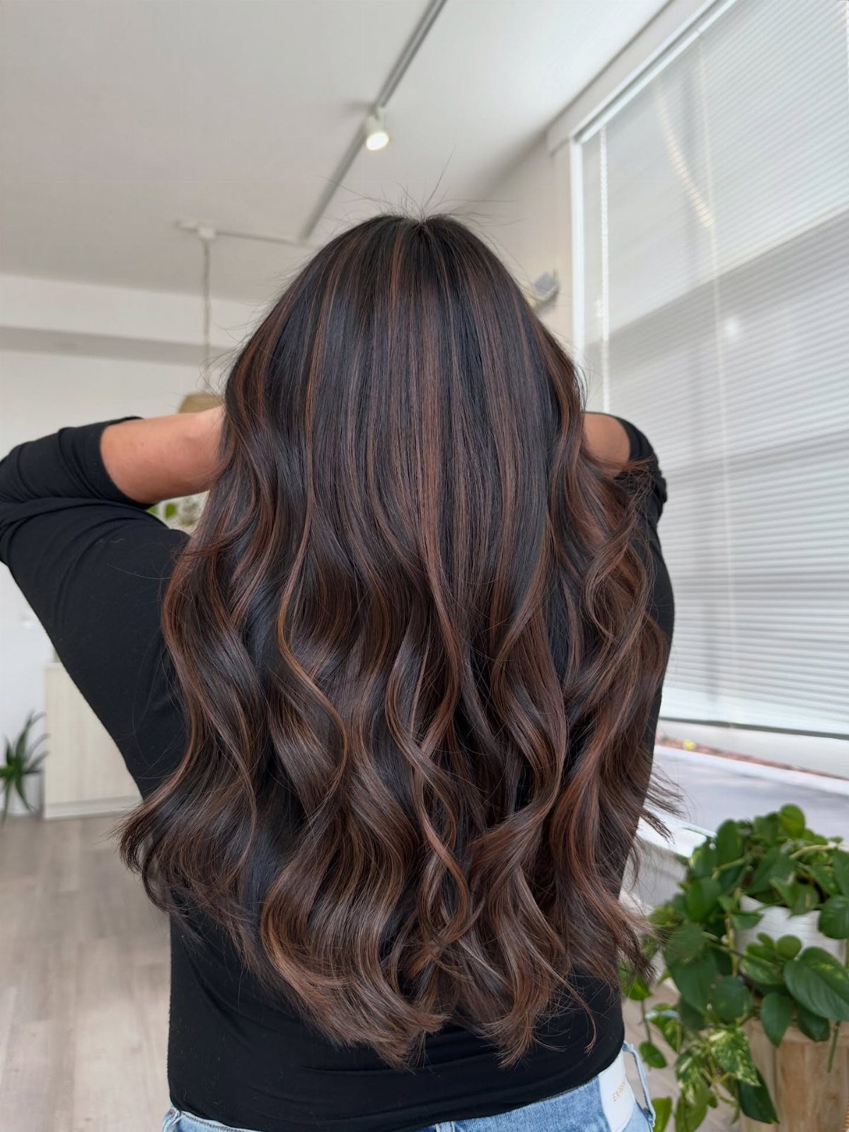 Long wavy dark hair with hazelnut highlights seen from the back.