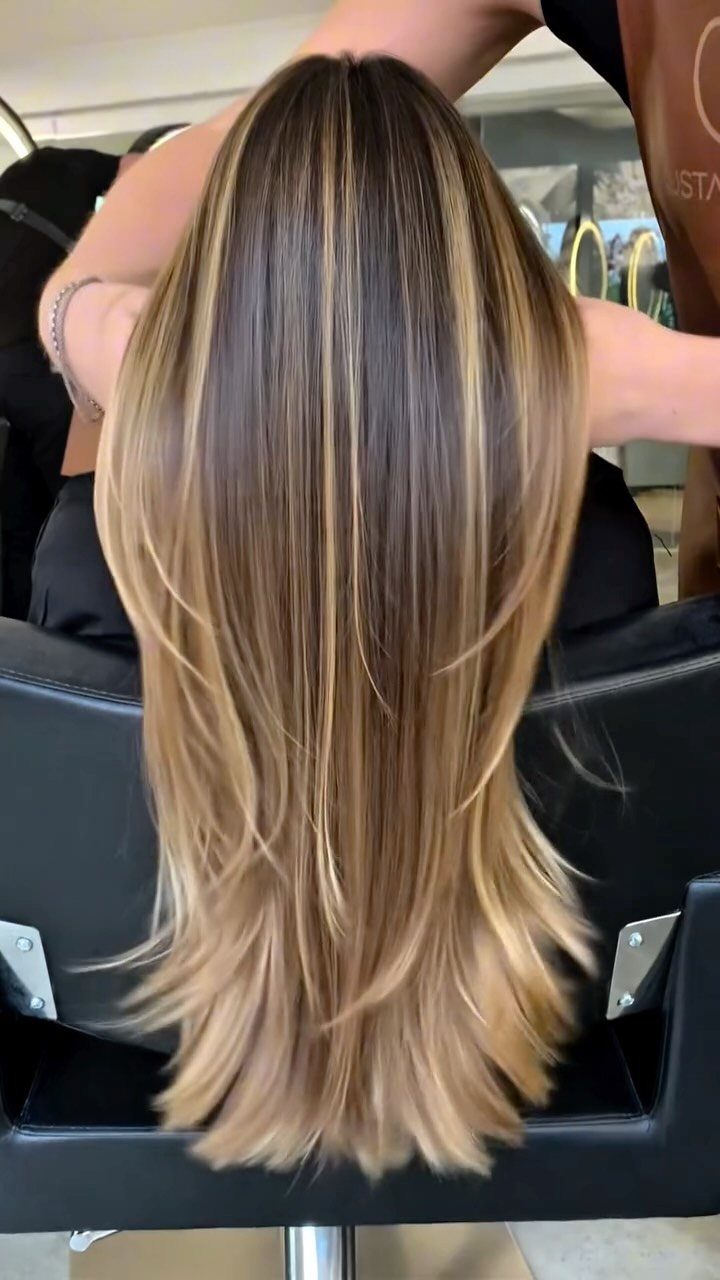 Long straight hair with hazelnut brown tones and golden blonde highlights in salon