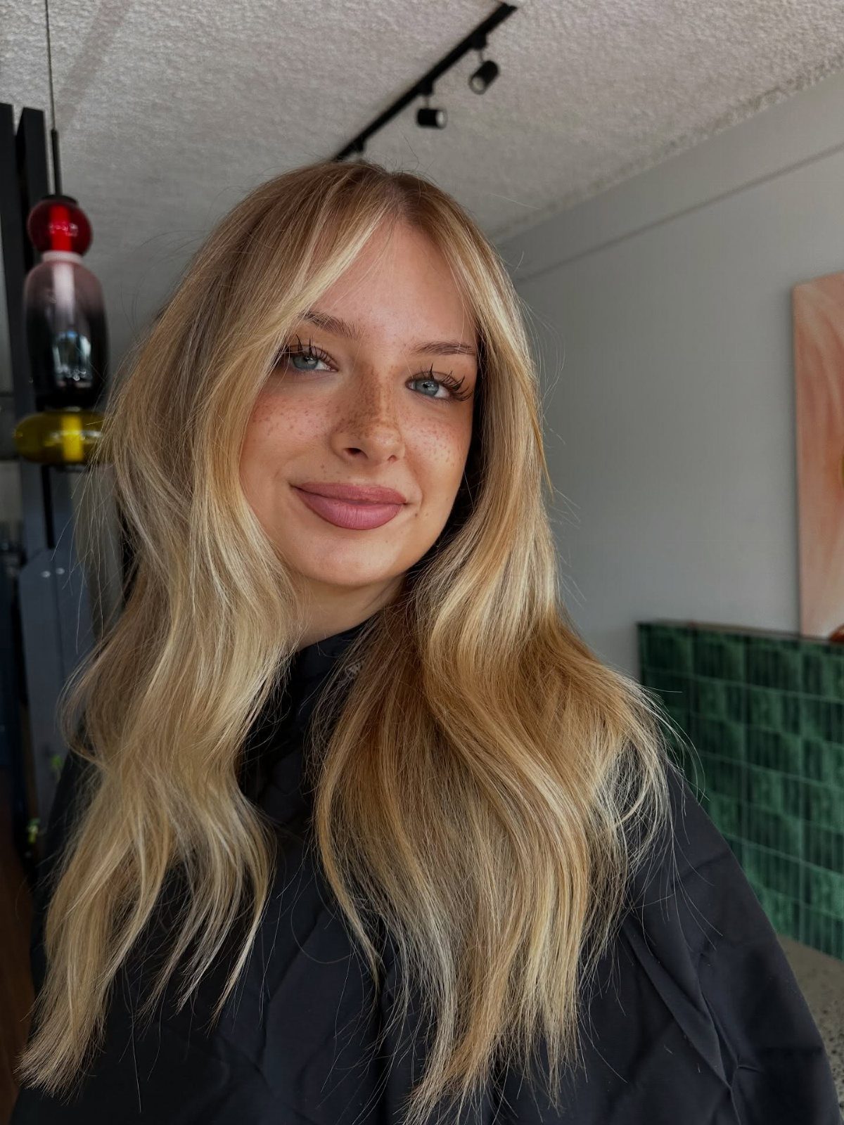 8 Honey Blond with Highlights Ideas for Every Look 2 Woman with long honey blonde hair and dark roots posing indoors.