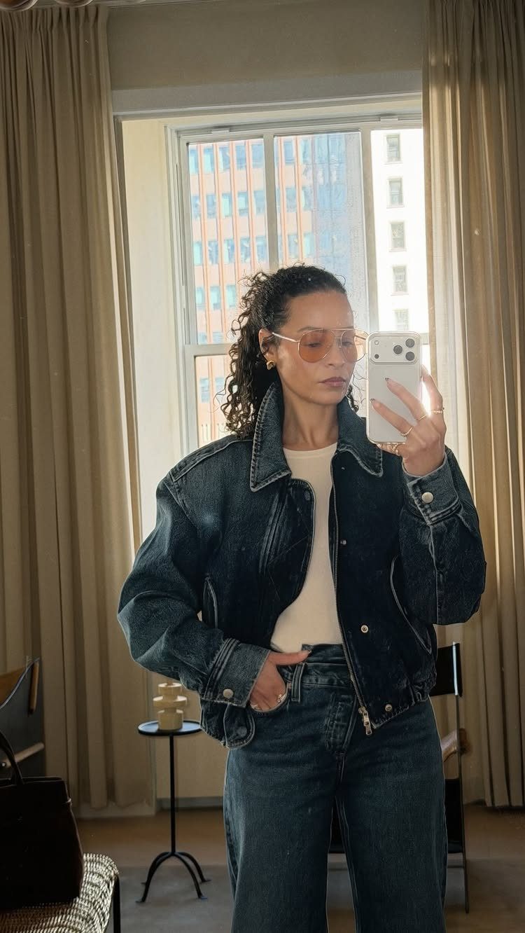 Woman wearing a dark blue denim jacket and matching jeans in a mirror selfie.