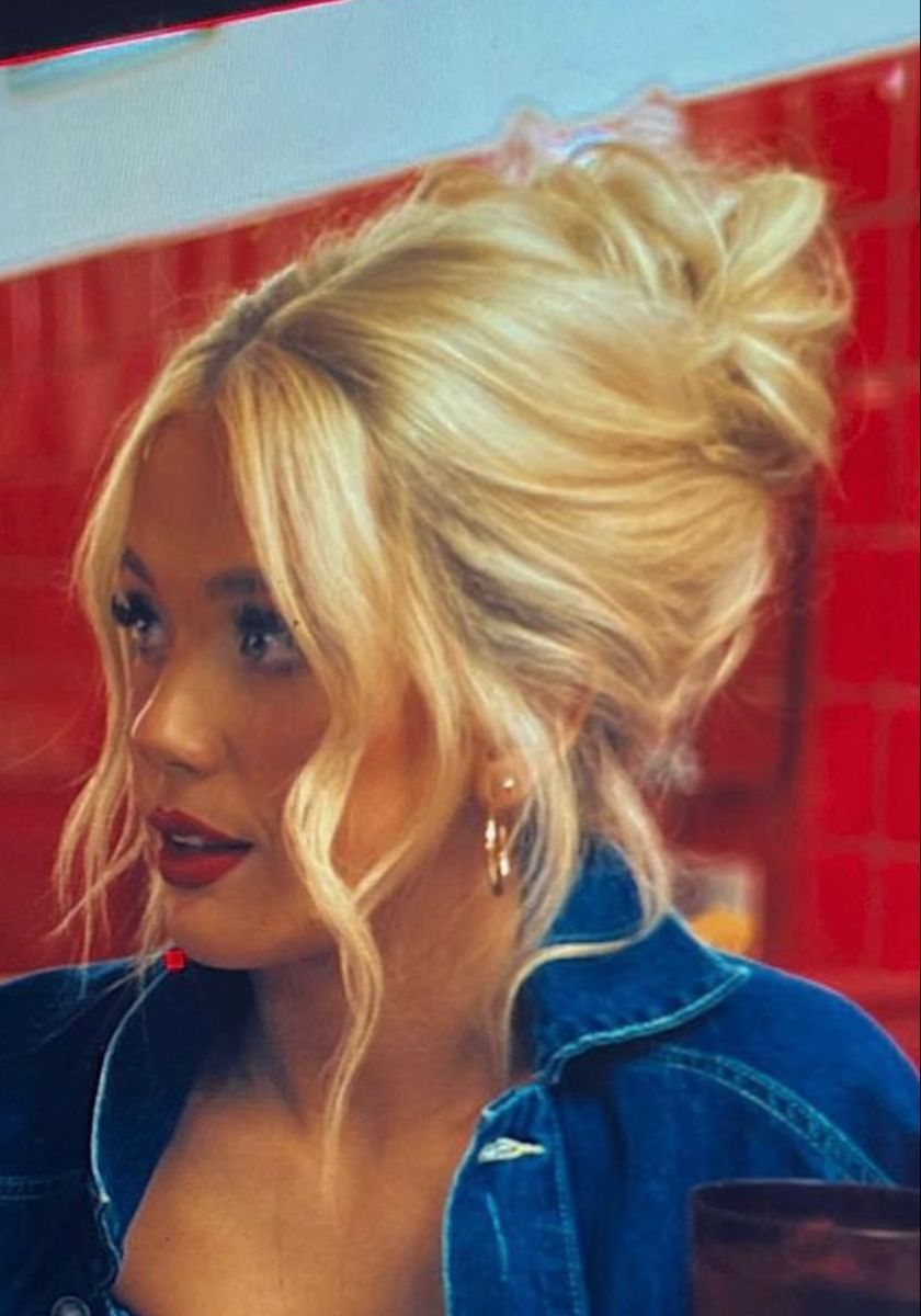 Woman with blonde hair in a voluminous bumped-up updo and denim shirt.