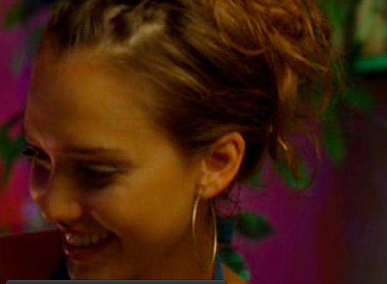 Woman with honey-blonde hair in a messy updo wearing gold hoop earrings.