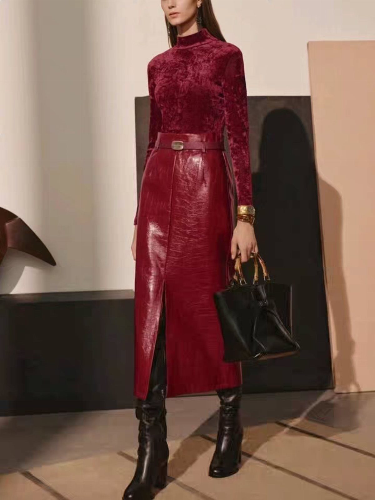 Woman wearing a claret velvet top and claret leather midi skirt with black boots