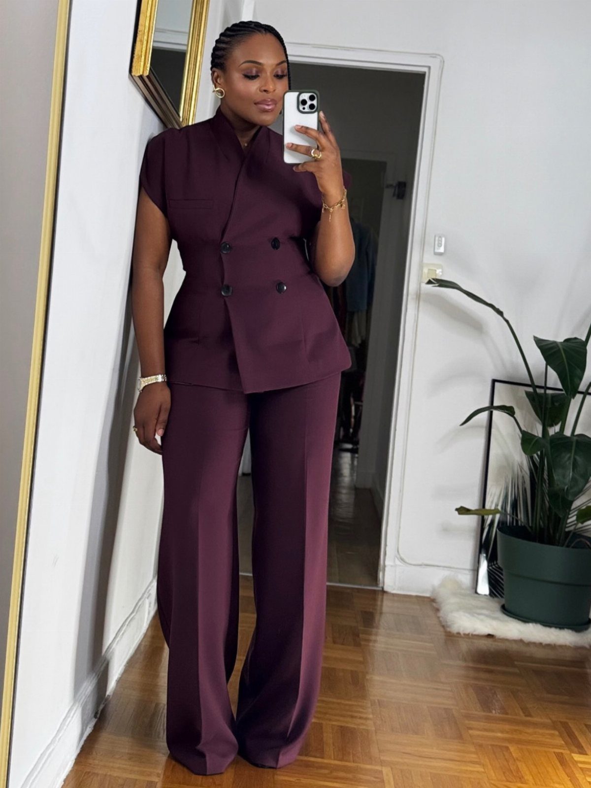 Woman wearing a plum-colored double-breasted blazer and matching wide-leg trousers in a room.