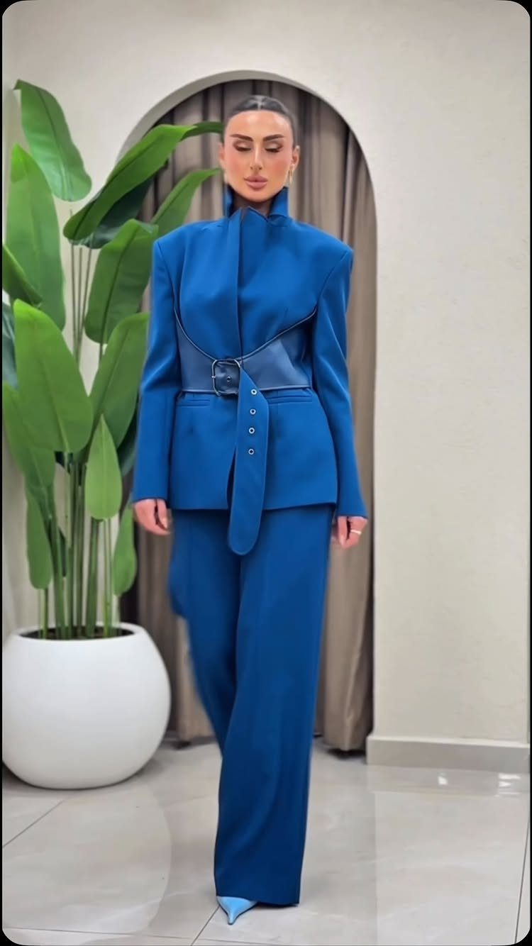 Woman in a royal blue structured suit with a wide leather belt and trousers.