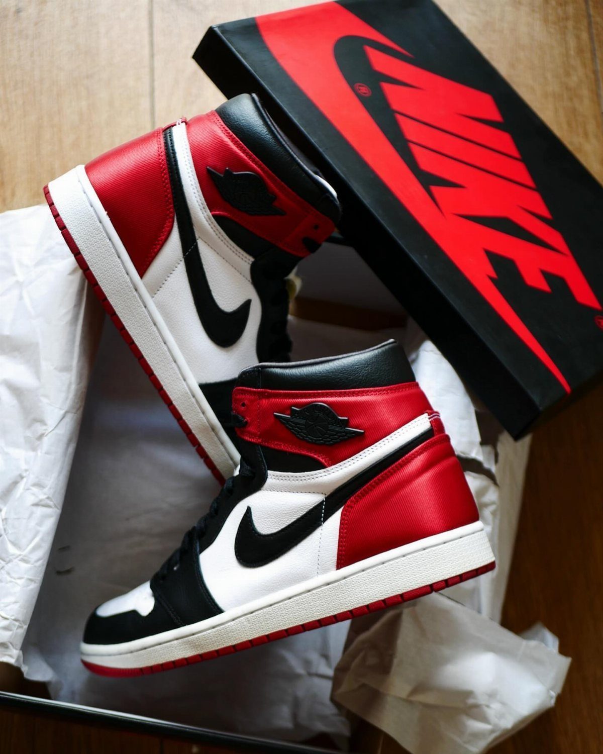 Red, white, and black Air Jordan 1 sneakers in a box with Nike packaging.