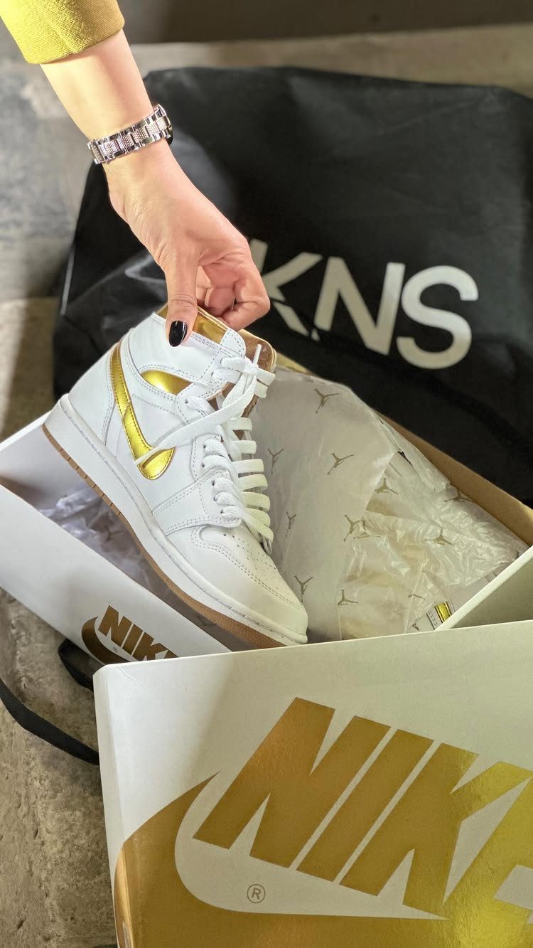White Air Jordan 1 sneakers with metallic gold accents inside a Nike shoebox