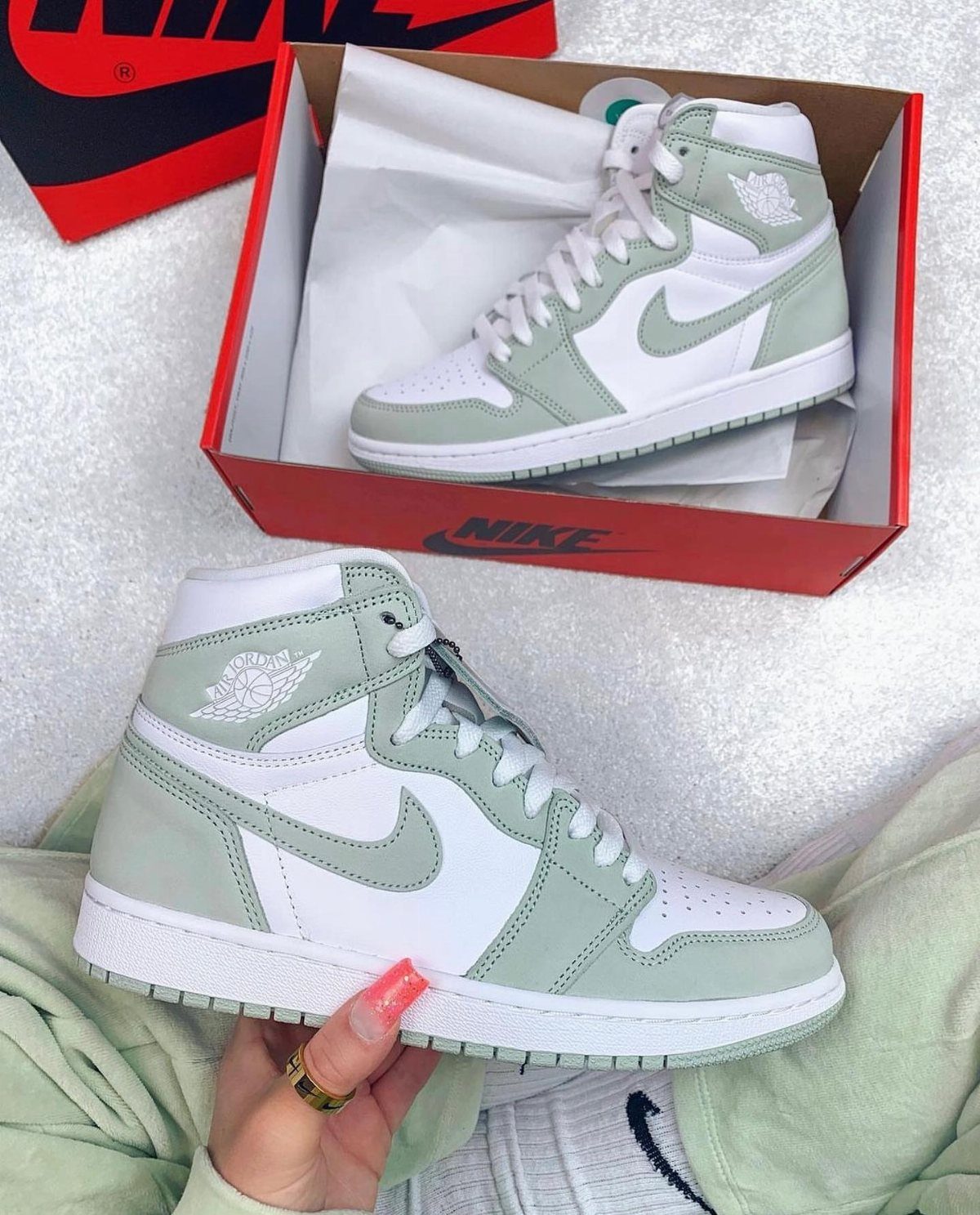 Seafoam green and white Air Jordan 1 sneakers, one held and one in box.