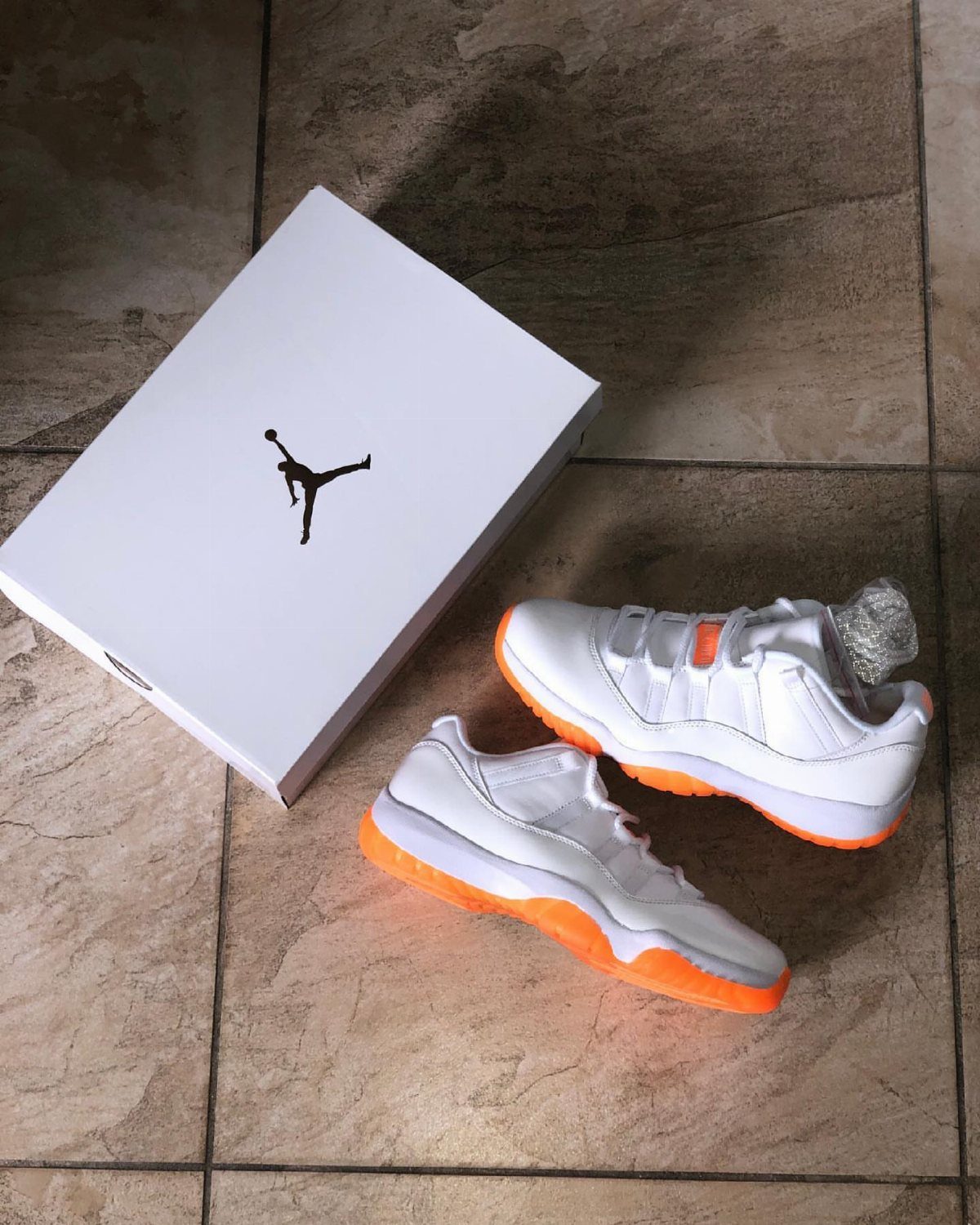 White Air Jordan 11 Low Citrus sneakers with orange soles and white shoebox.