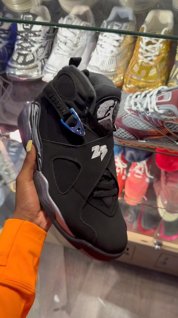Black Air Jordan 6 sneaker with chrome details held in front of display case