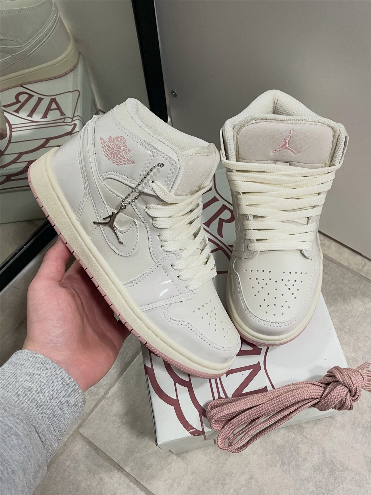 White high-top Air Jordan sneakers with pink accents resting on a branded box.