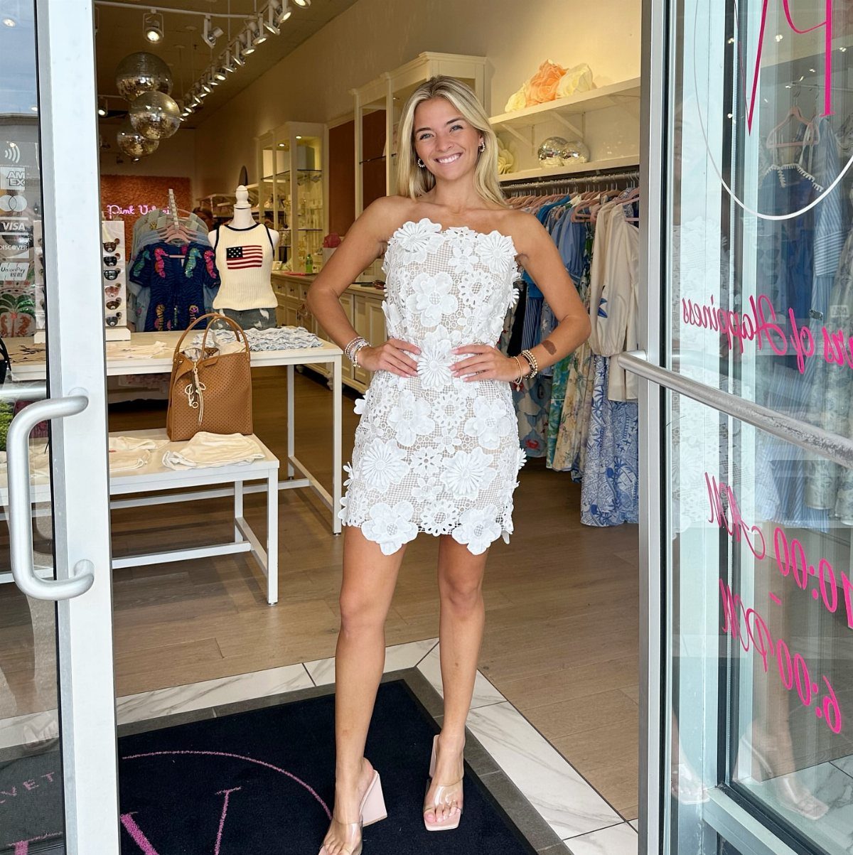 Lace Dress Short Ideas: 5 Looks for Parties and Dates 3 Woman wearing a strapless white lace mini dress posing in a clothing boutique doorway.