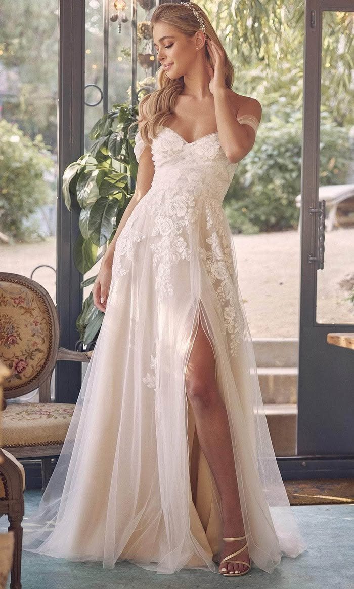 Woman in ivory floral lace wedding dress with off-the-shoulder straps and leg slit