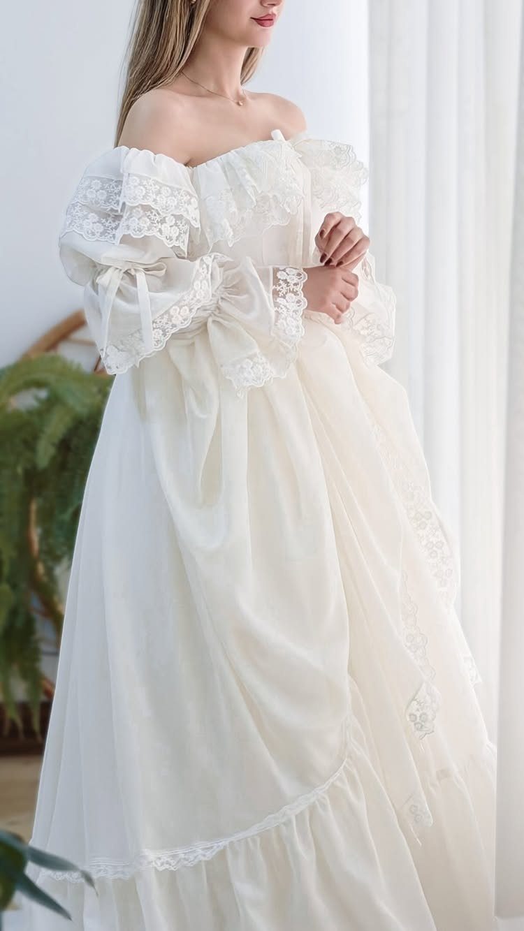 Woman wearing a white lace dress with puff sleeves and a tiered flowy skirt