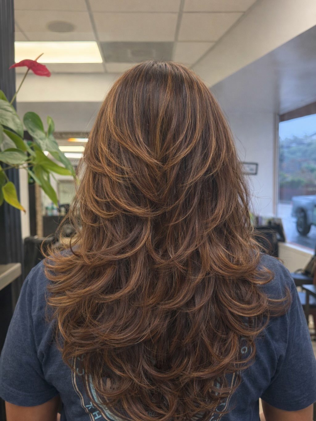 Long reddish-brown hair with voluminous cascading layers and curled ends from behind.
