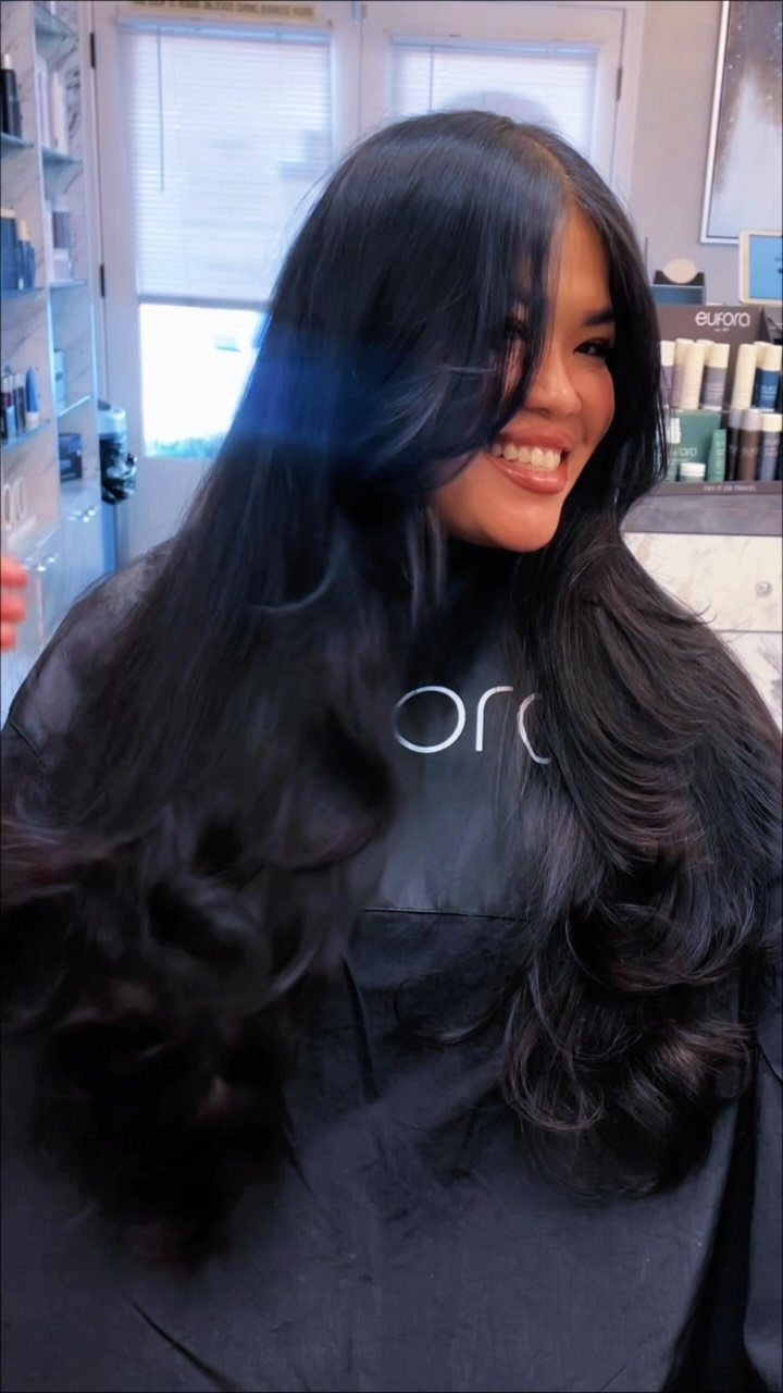 Woman with long, thick dark hair styled in voluminous layers and curls.