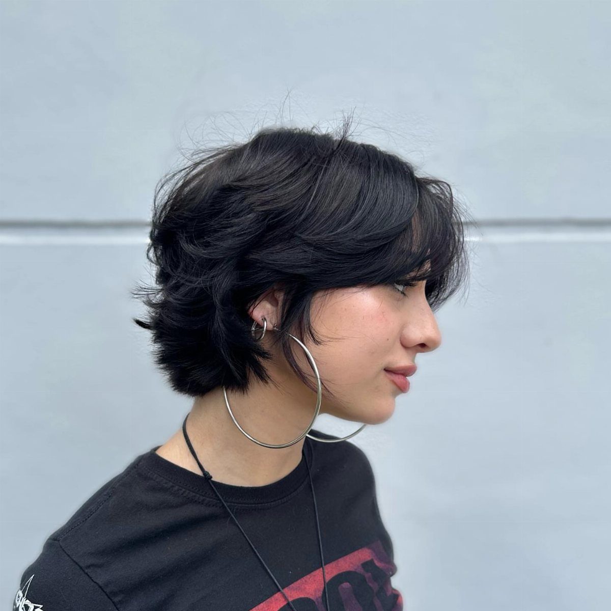 Person with a short black bixie haircut and large silver hoop earrings.