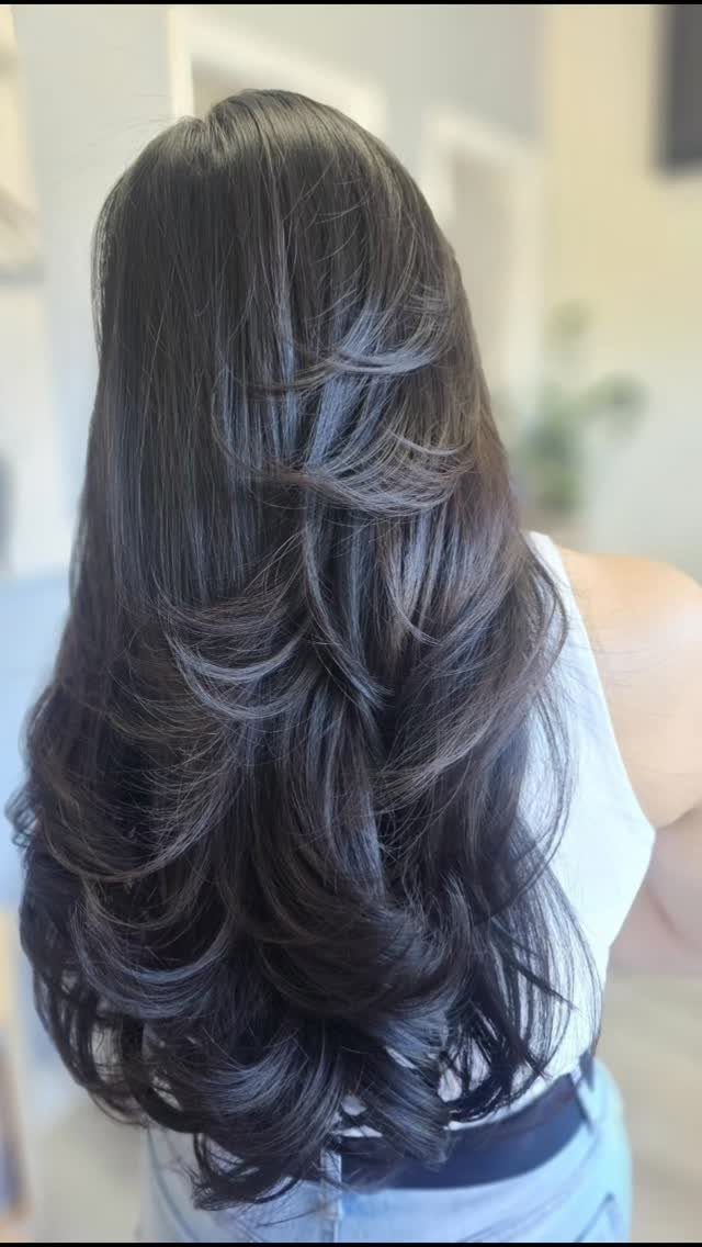 Long dark brown hair with voluminous wavy layers and curled ends from behind.