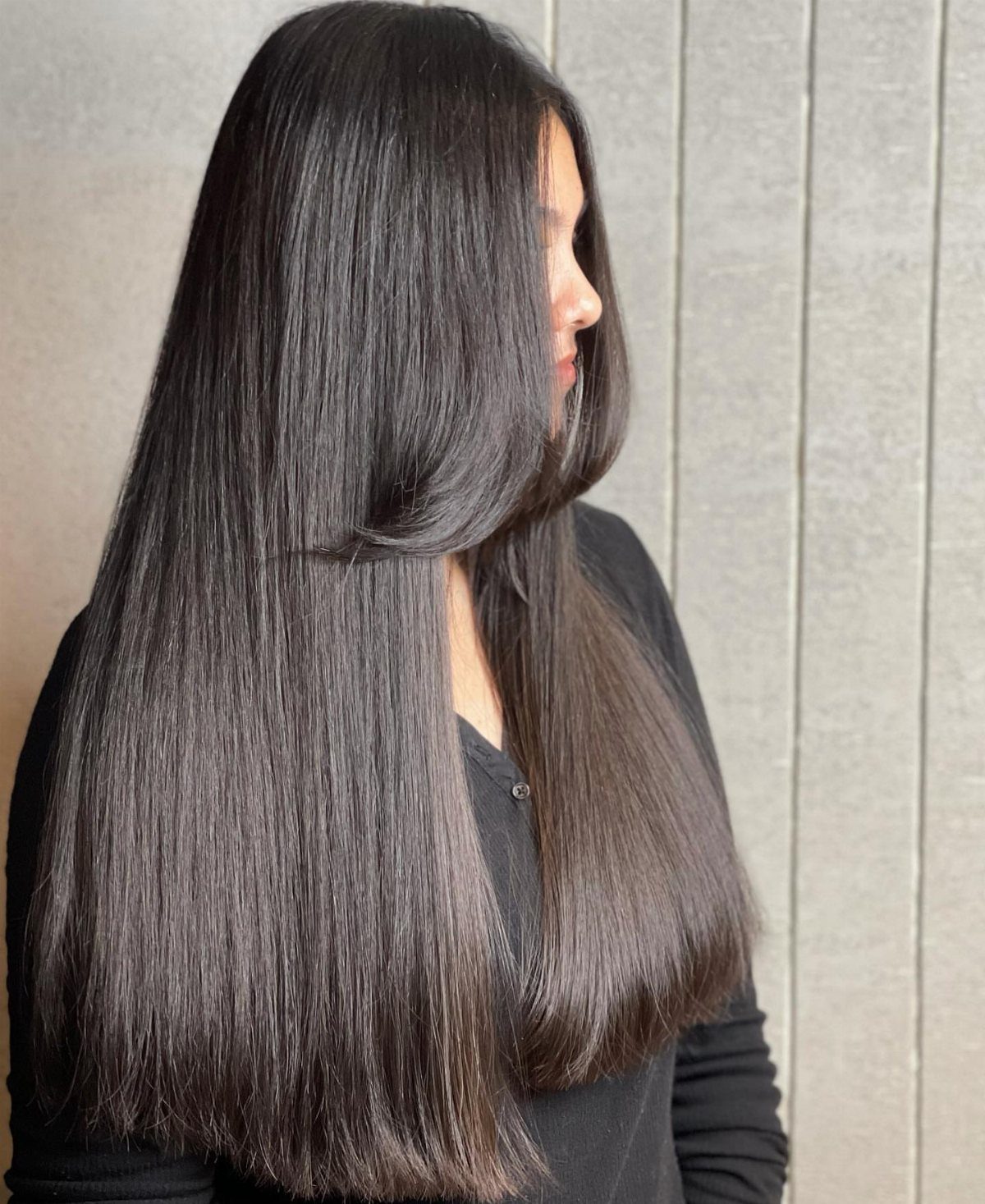12 Long Brown Hair Ideas with Highlights, Curls and Layers 12 Woman with long, straight, glossy dark brown hair posing against a grey wall.