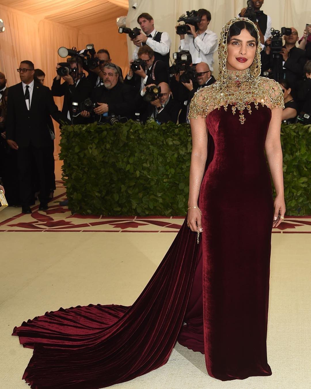 Priyanka Chopra in a red velvet gown with a gold beaded capelet and headpiece.