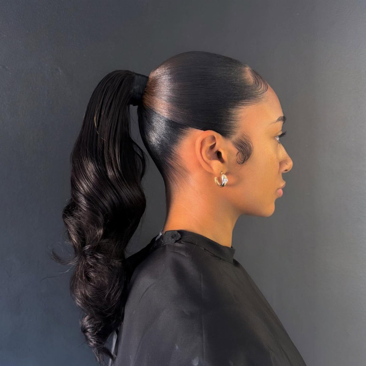10 Natural Curls Hairstyles for Every Length and Style 4 Woman with a sleek slicked back high ponytail and polished curly ends.