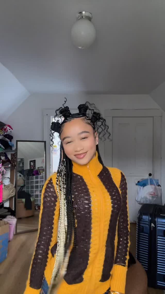 10 Natural Curls Hairstyles for Every Length and Style 7 Woman with curly space buns and long braids wearing a yellow patterned sweater.