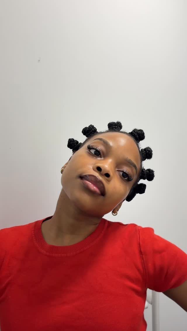 Natural Hair Beauty Looks: 11 Styles From Buns to Locs 3 Woman with dark skin wearing a red shirt and hair in Bantu knots.