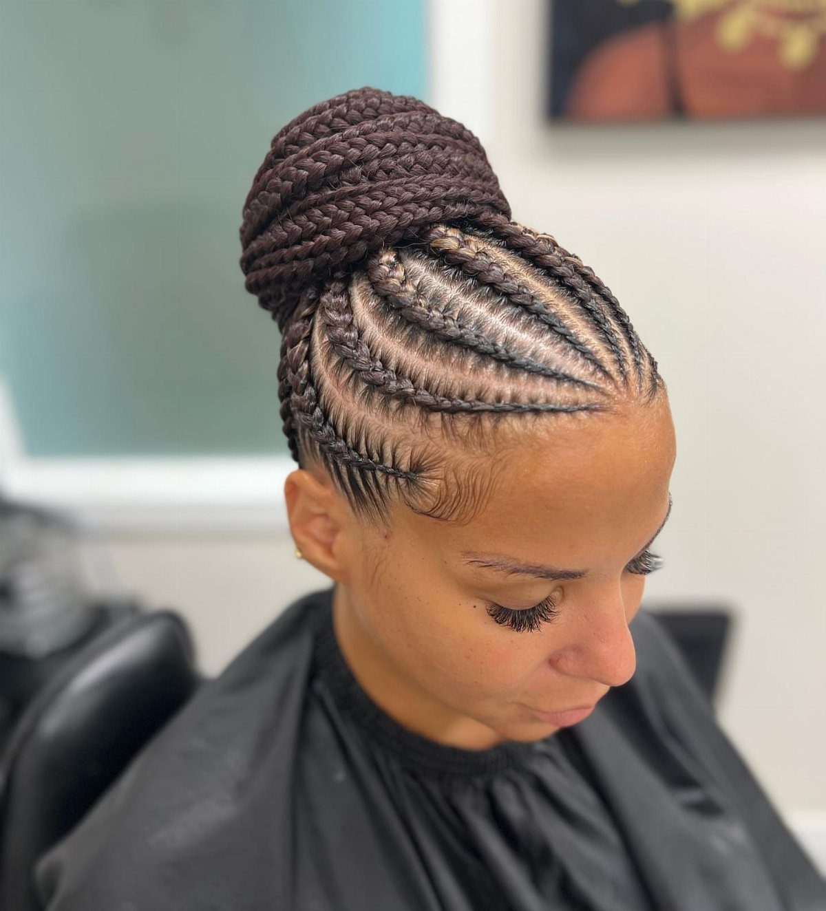 Natural Hair Beauty Looks: 11 Styles From Buns to Locs 6 Woman with dark brown cornrows styled into a high braided bun updo.