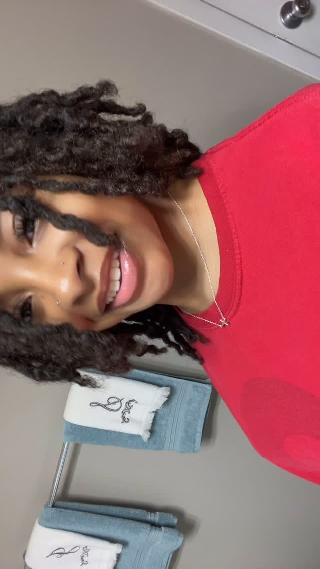 Natural Hair Beauty Looks: 11 Styles From Buns to Locs 10 Smiling woman with dark brown locs wearing a bright red shirt.