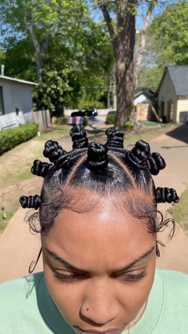 Woman with black hair styled in small coiled Bantu knots outdoors.