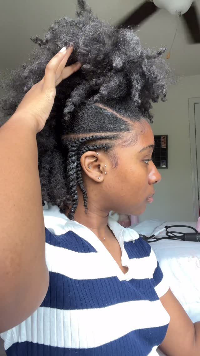 Woman with a frohawk hairstyle featuring braided sides and voluminous curly top hair.