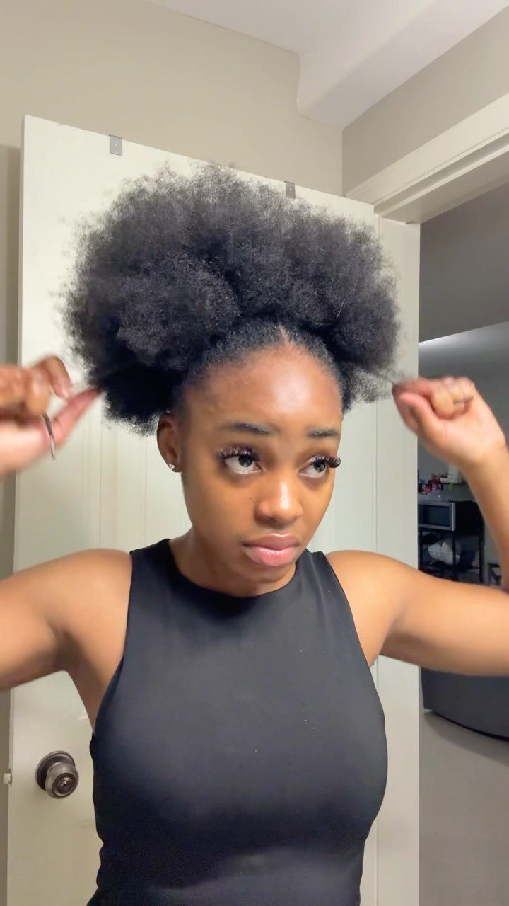 Woman with natural black hair styled in a voluminous high puff hairstyle.