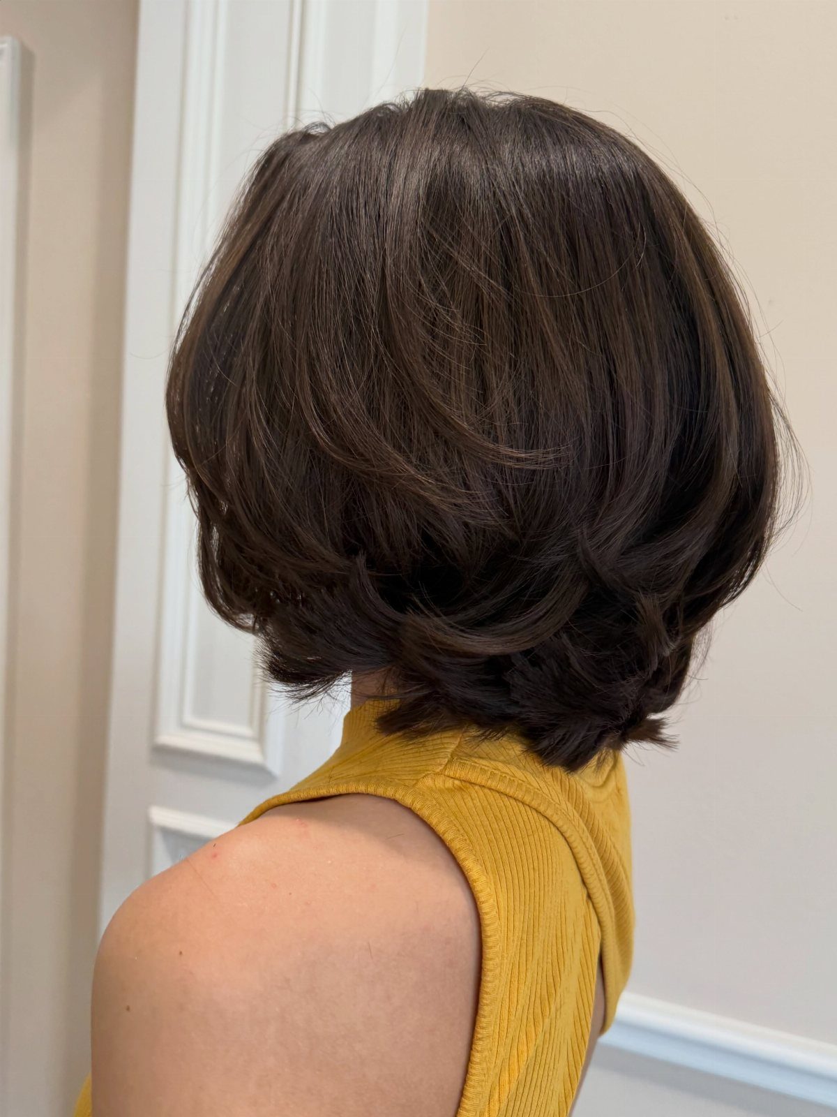 Woman with a voluminous brown chin-length bob featuring curved, layered ends.