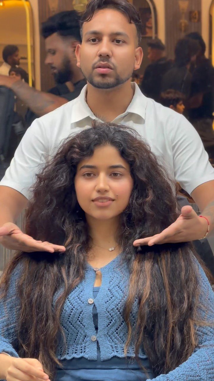 Woman with long curly layered brown hair posing with a hair stylist