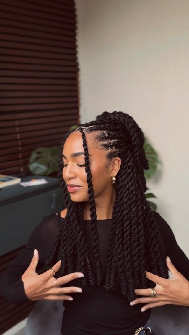 Woman with long black twists and cornrows wearing a black long-sleeved shirt.
