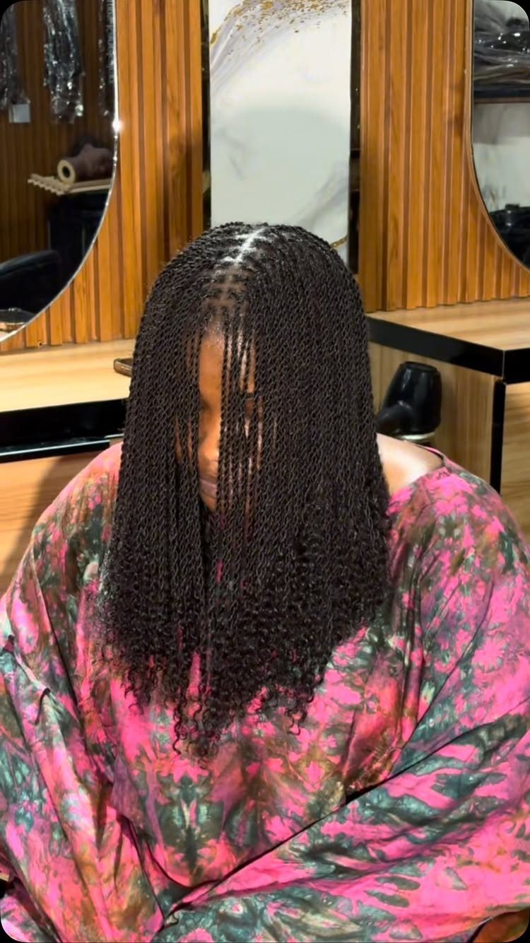 Person with long, curly dark passion twists wearing a pink tie-dye garment.